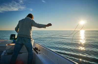 Standing in the boat throw the rope into the water
